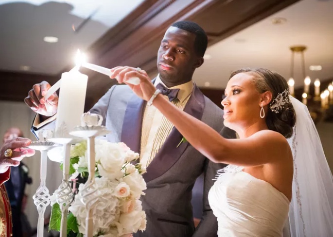 A bride and groom light the center unity candle during their wedding ceremony