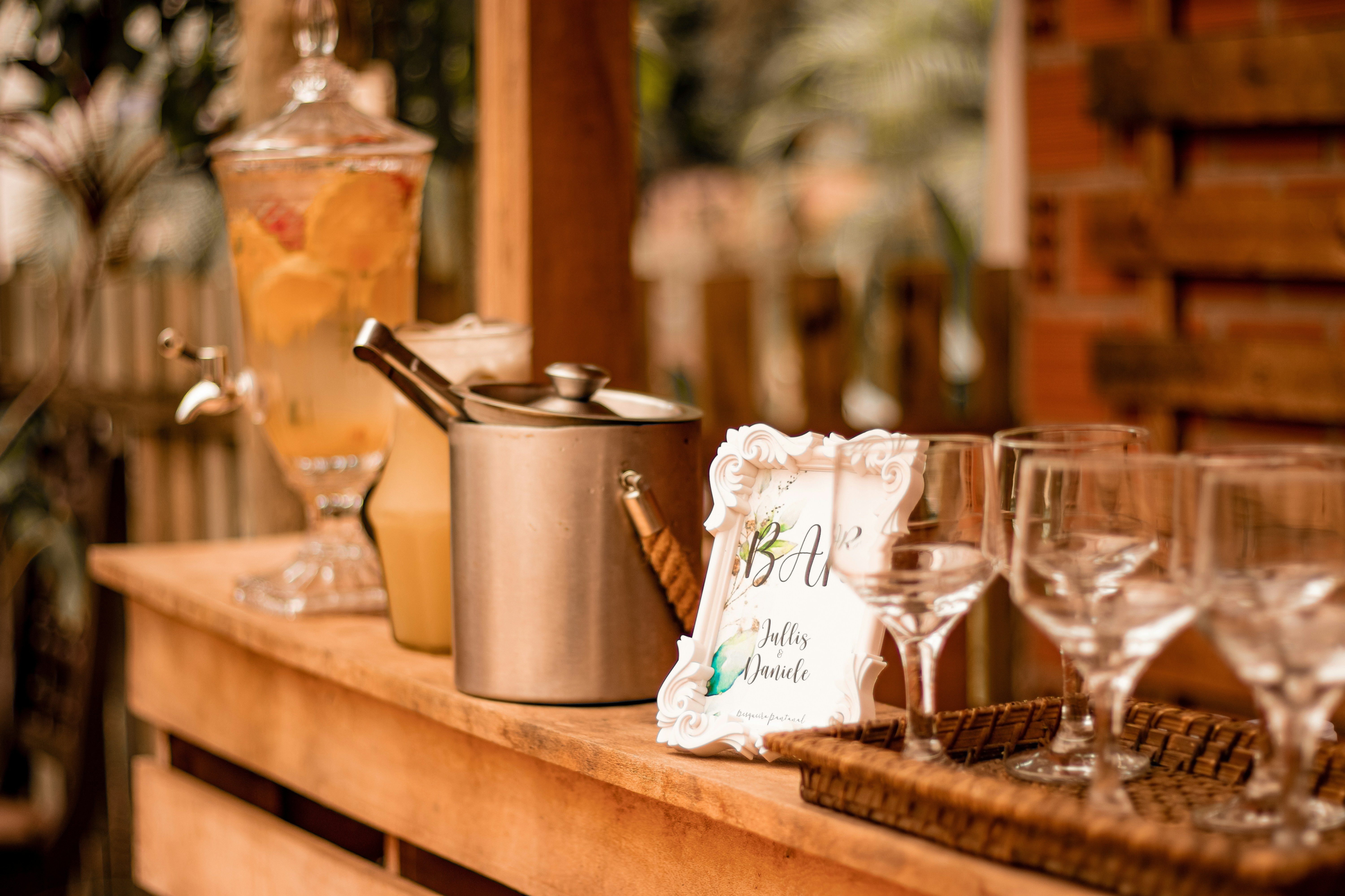 a wedding bar with empty glasses, a bar sign, ice, and self-serve cocktails
